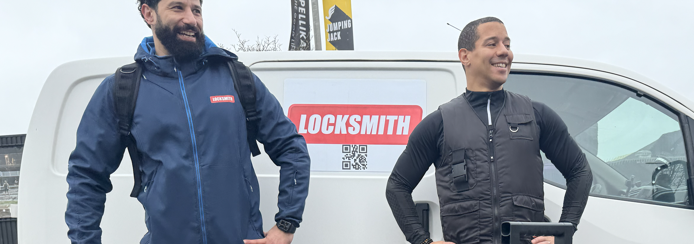 Twee slotenmakers naast bedrijfswagen met logo.