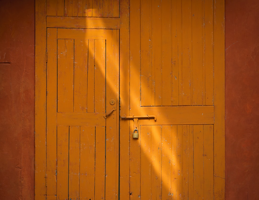 Geel geschilderde houten deur met hangslot.