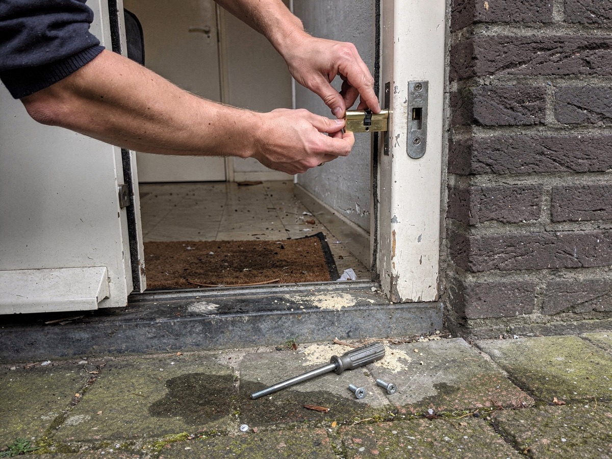 Handen plaatsen een nieuwe europrofielcilinder in de voordeur van een huurwoning