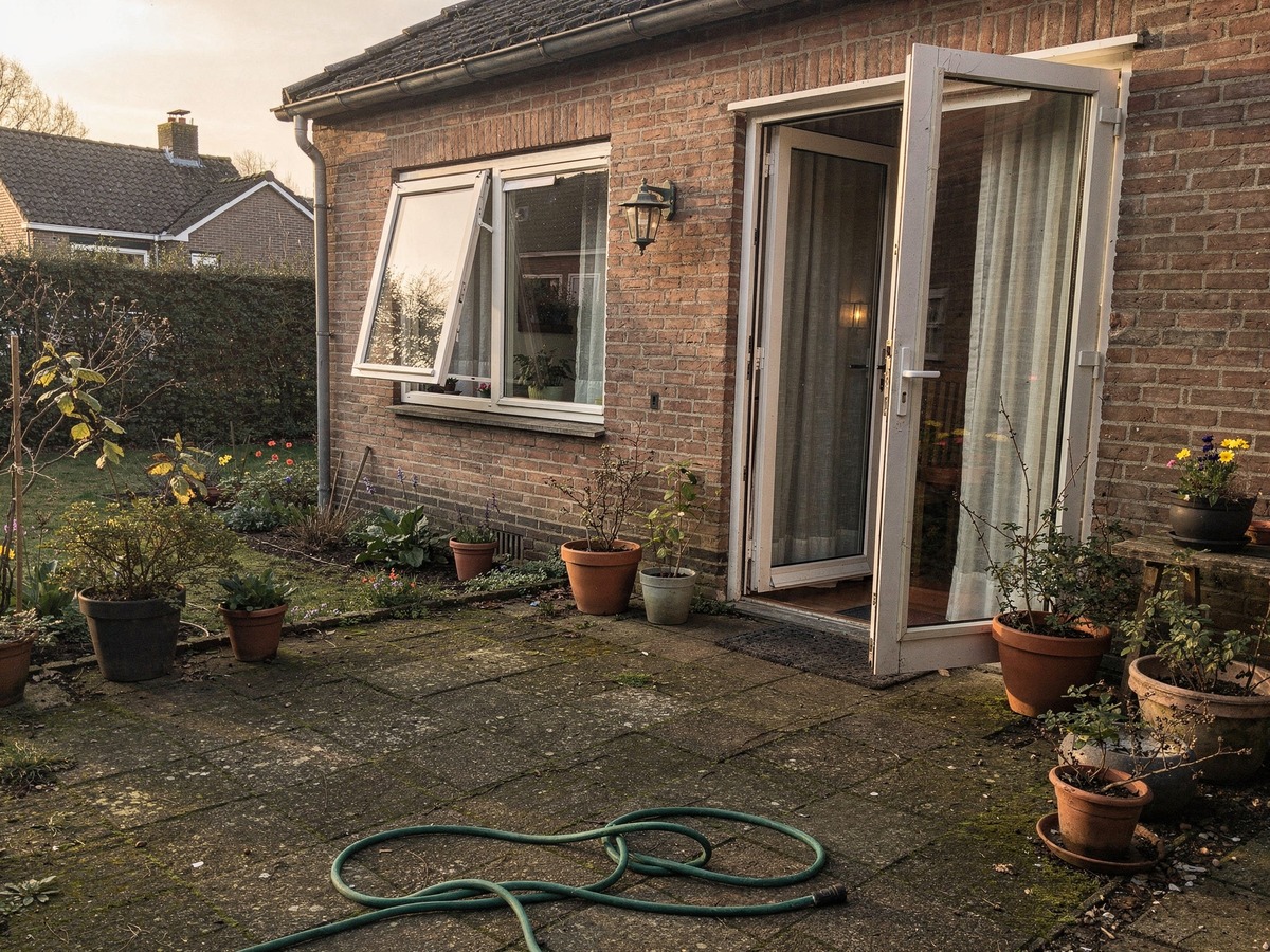 Openstaande tuindeur en gekanteld raam aan de achterzijde van een Nederlandse woning