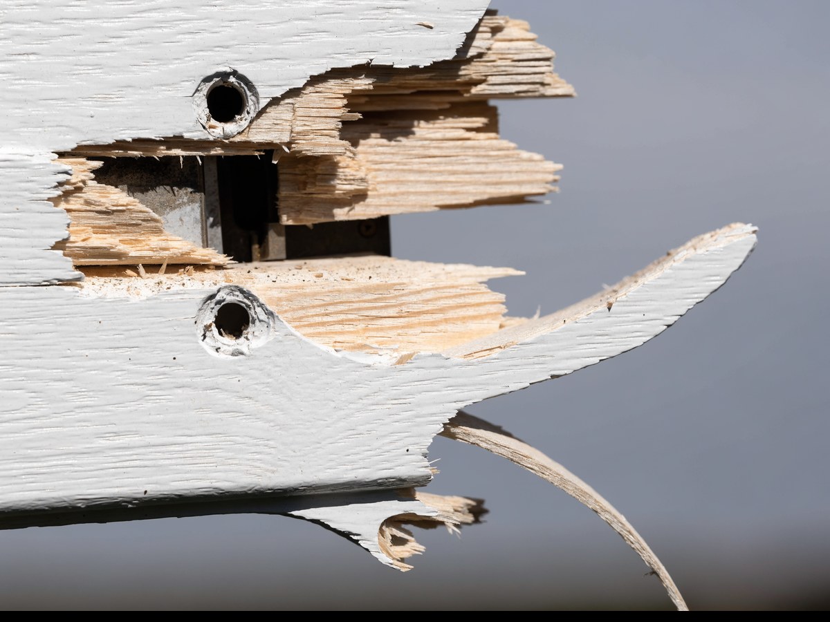 Verse inbraakschade aan een wit houten deurkozijn met gesplinterd hout en uitgescheurde schroefgaten naast de sluitplaat