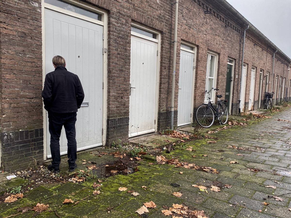 Person seen from behind standing at a closed front door of a Dutch terraced house after being locked out